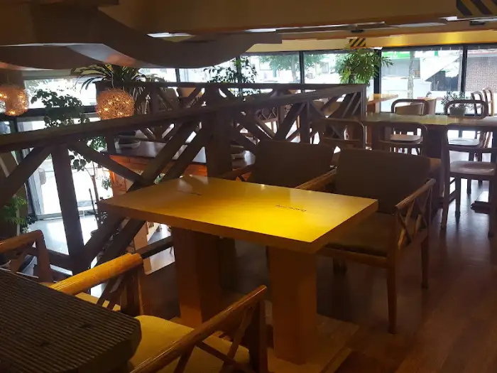 카페 내부 테이블과 의자가 놓여 있는 모습, 창밖으로 외부 풍경이 보인다