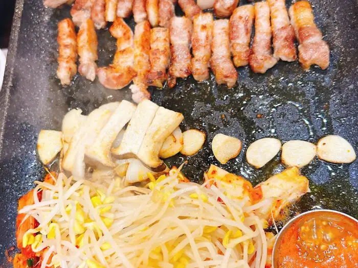 불판 위에 올라간 삼겹살과 곁들임 재료