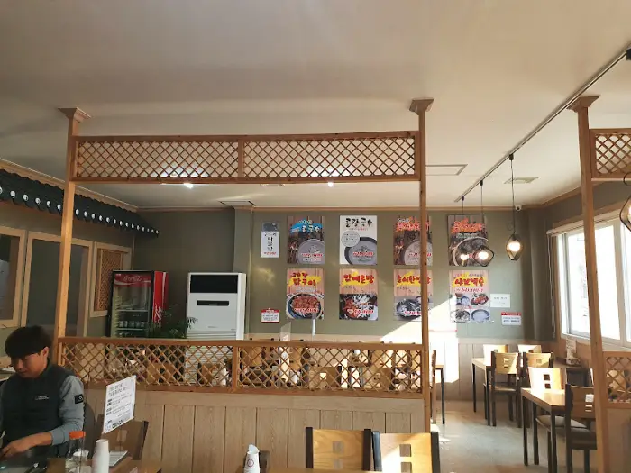 청주 OO 칼국수 내부 모습, 메뉴판들이 걸려있고 테이블과 의자들이 보인다.