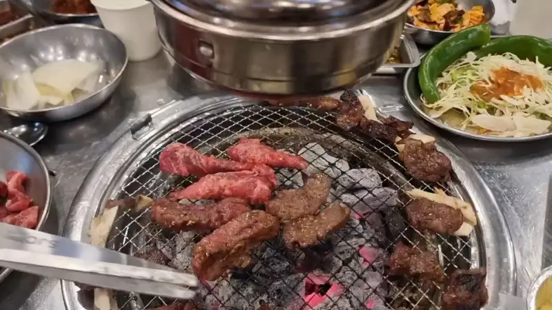 숯불 위에 올려진 소갈비살과 다채로운 밑반찬