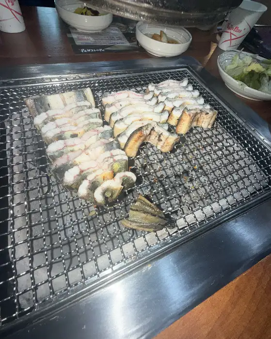숯불 위에서 여러 덩어리의 장어가 구워지고 있는 모습