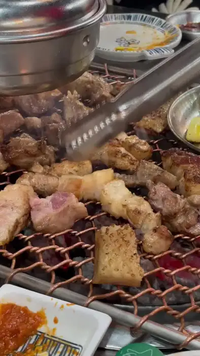 직원이 집게로 고기를 뒤집으며 굽고 있는 모습