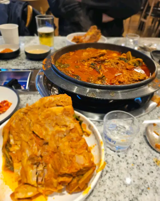 테이블에 차려진 푸짐한 감자탕과 뼈다귀, 소주 한 잔