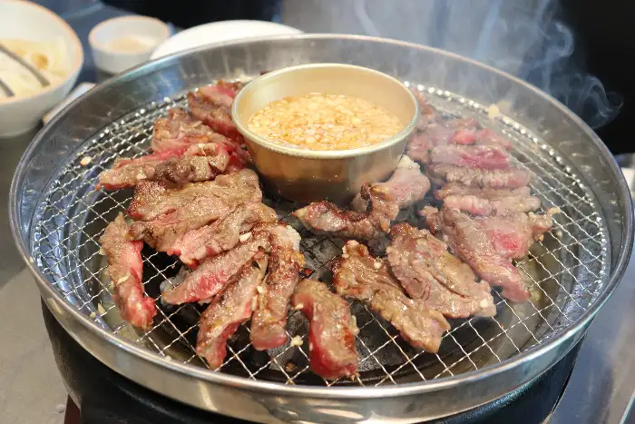 숯불 위에서 익어가는 고기들과 곁들임 소스