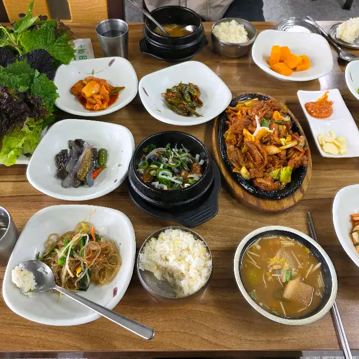 밥과 제육볶음, 반찬들을 섞어 비벼 먹는 모습