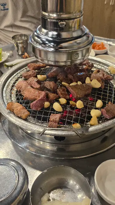 숯불 위에서 지글지글 구워지는 삼겹살과 마늘, 버섯