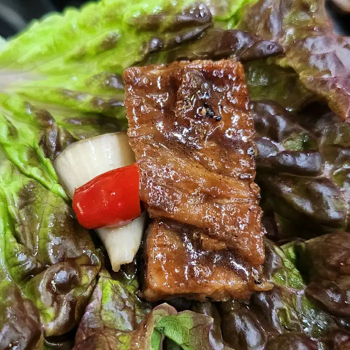 상추와 깻잎 위에 올라간 돼지갈비 한 점