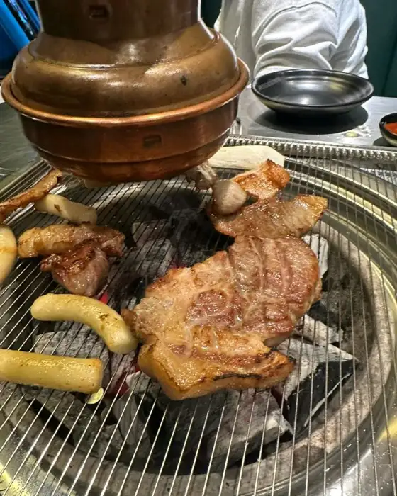 숯불 위에서 구워지고 있는 두툼한 돼지고기.