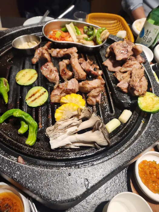 잘 구워진 고기와 함께 버섯, 옥수수, 고추 등이 불판에 함께 올라가 익고 있습니다.