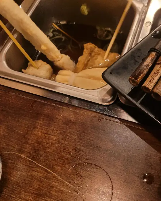 끓고 있는 어묵 국물 솥과 젓가락, 그리고 접시 일부가 보이는 클로즈업 샷