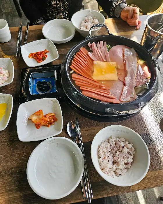 부대찌개 냄비와 밥, 숟가락, 젓가락 등이 놓인 모습