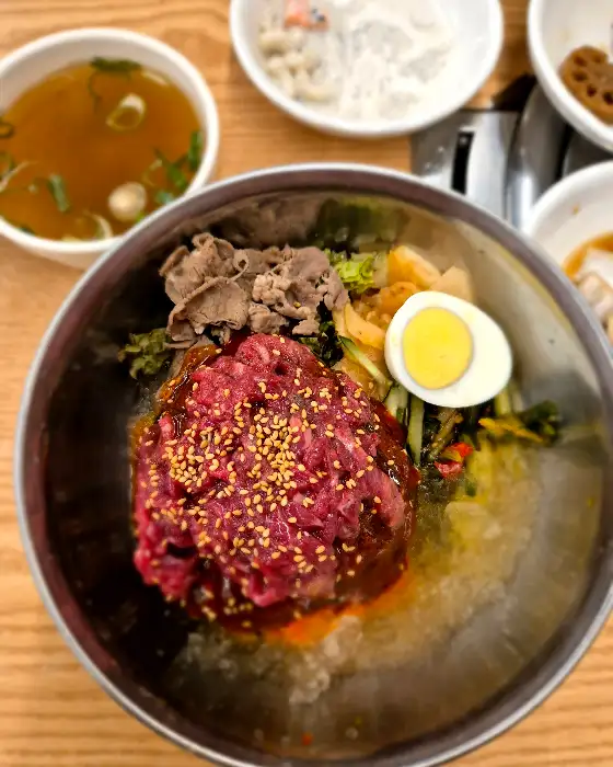 푸짐한 양의 비빔냉면, 신선한 채소와 고기가 어우러진 모습