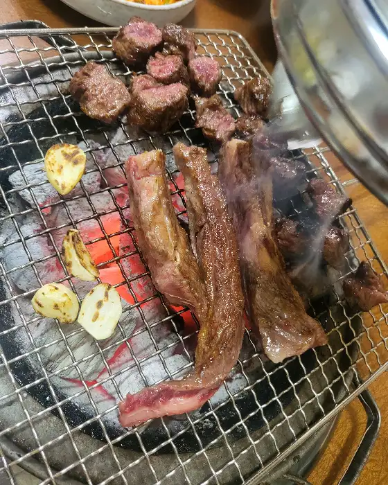 숯불 위에서 지글거리는 고기와 마늘
