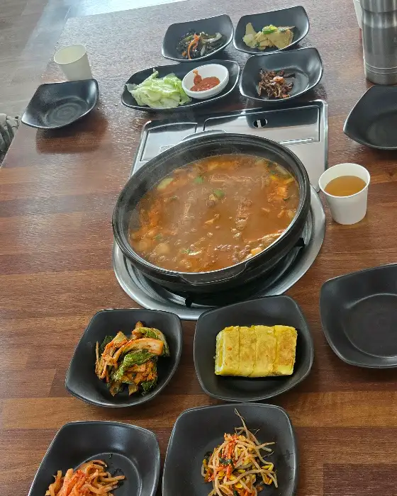 테이블 위에 놓인 청국장 전골과 여러 가지 밑반찬들