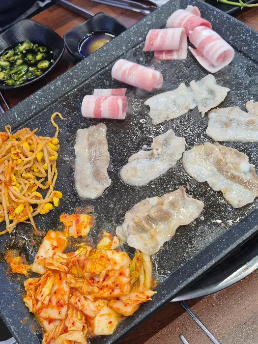철판 위에서 익어가는 대패 삼겹살과 곁들임 메뉴들