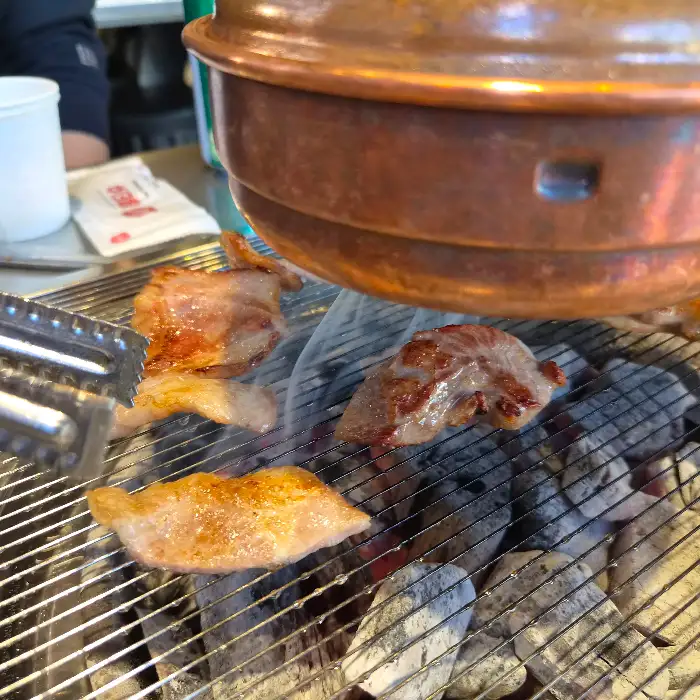 숯불 위에서 익고 있는 돼지고기 조각들과 껍데기.