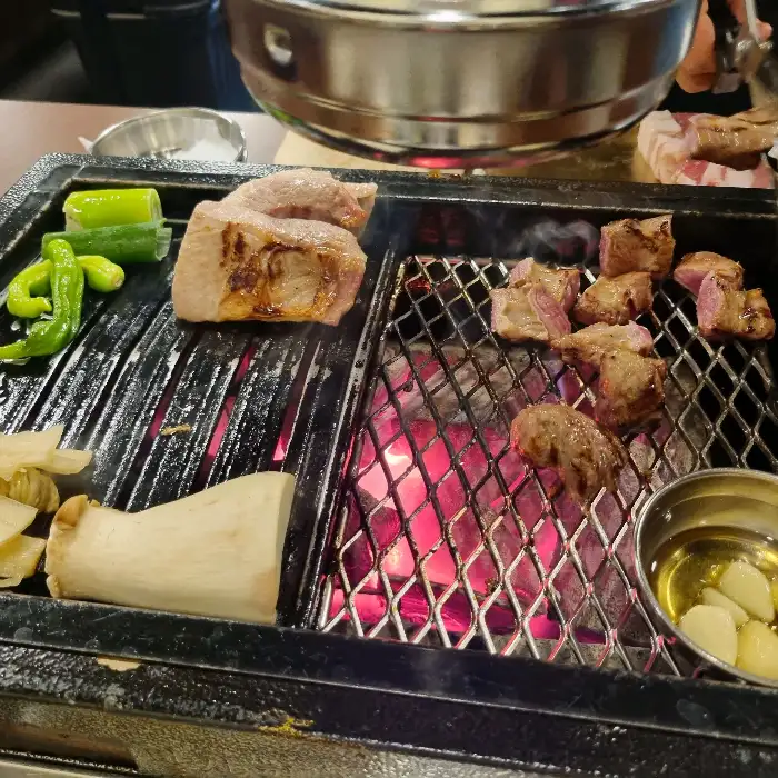 숯불 위에서 맛있게 구워지고 있는 삼겹살과 버섯