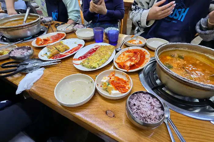 식탁 위에 계란말이, 김치, 밥, 국 등이 놓여 있다.