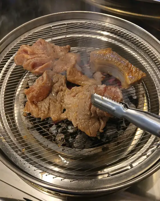 숯불 위에서 맛있게 익어가는 돼지고기 조각들