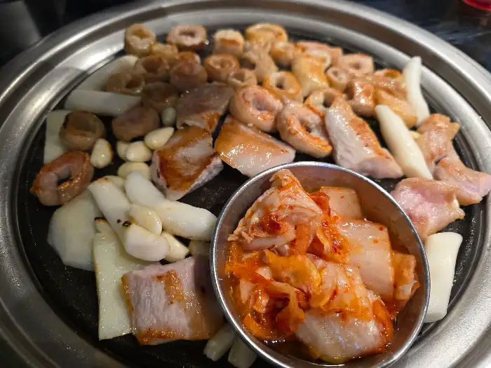 노릇하게 구워지고 있는 돼지막창과 떡, 마늘