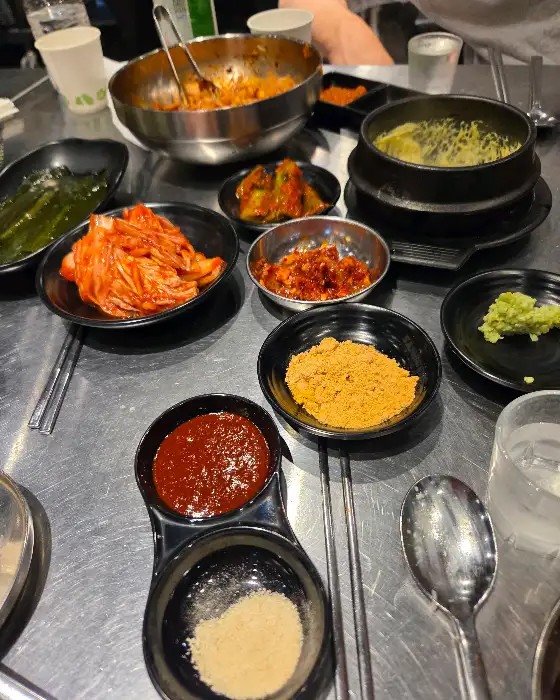 테이블 위에 차려진 다양한 밑반찬과 찌개, 밥.