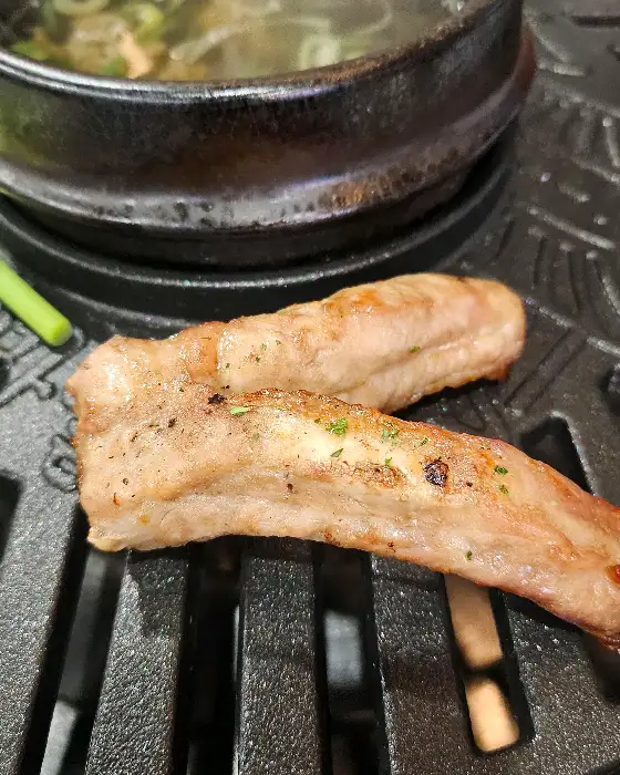 그릴 위에서 익어가고 있는 쪽갈비와 곁들임 메뉴