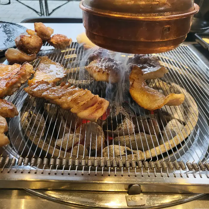 숯불 위에서 노릇하게 익어가는 삼겹살과 껍데기.