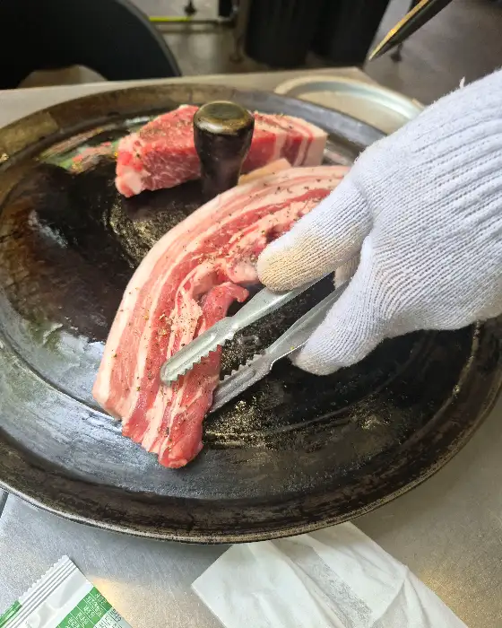 두툼한 목살을 집게로 집는 모습