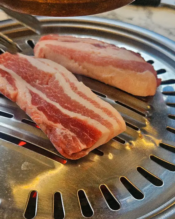 두툼한 삼겹살이 불판에 올라가 구워지고 있다.