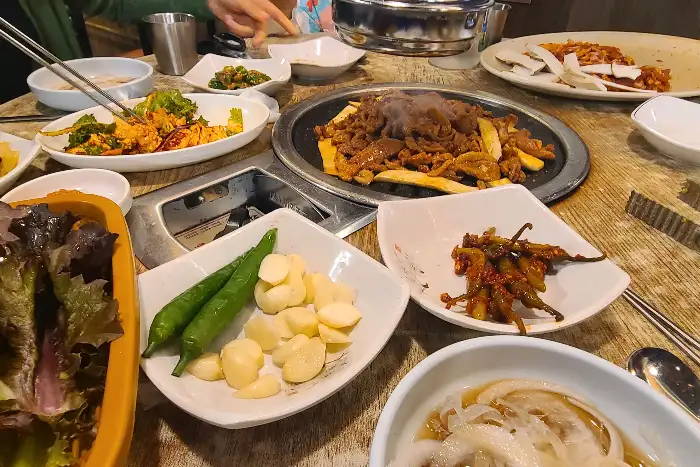 식탁 가득 차려진 푸짐한 오리구이와 반찬들