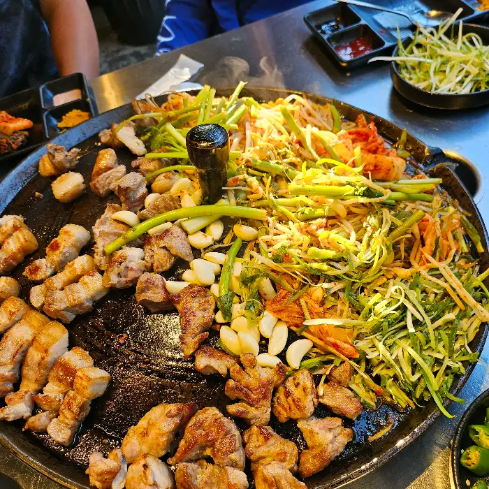 솥뚜껑에 구워지는 푸짐한 삼겹살과 채소