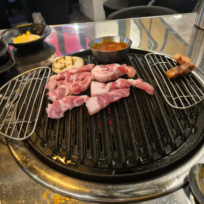 잘 익은 꼬들살과 삼겹살 조각들이 불판 위에서 지글거리는 모습
