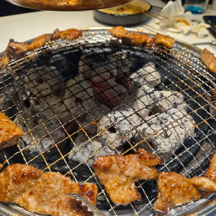 숯불 위에서 구워지고 있는 삼겹살과 다른 부위 고기들