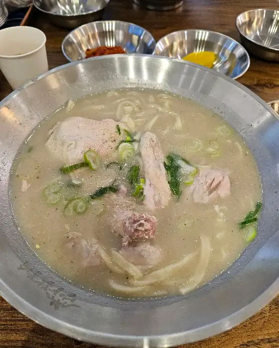 닭칼국수가 담긴 뚝배기와 곁들임 반찬