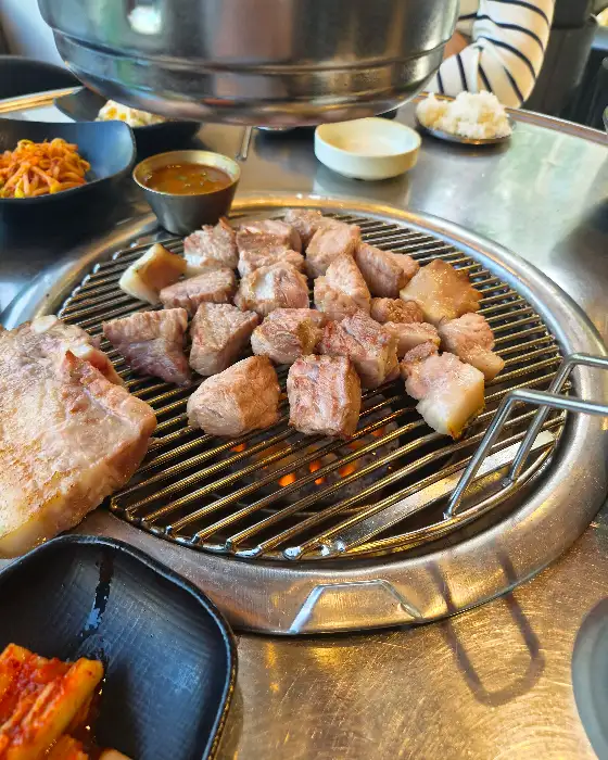 잘 익은 흑돼지 구이와 멜젓, 그리고 쌈채소가 준비되어 있다.