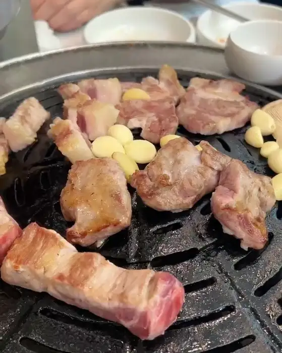 잘 익은 꽃삼겹살 한 점과 마늘, 꽈리고추