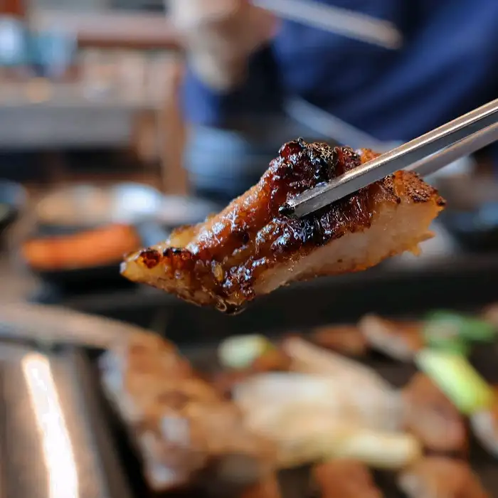 집게로 집어 올린 돼지갈비 조각의 단면