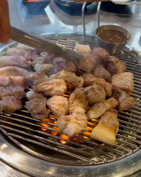 집게로 흑돼지 고기를 뒤집는 모습.