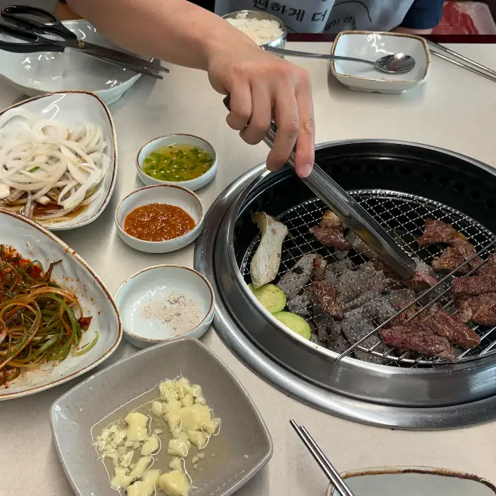 불판 위에서 익고 있는 고기와 곁들임 반찬