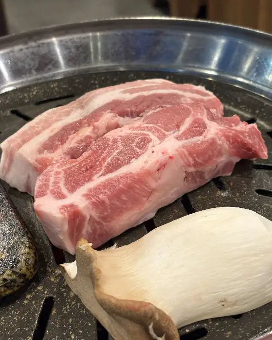 불판 위에 올려진 두툼한 목살과 새송이버섯