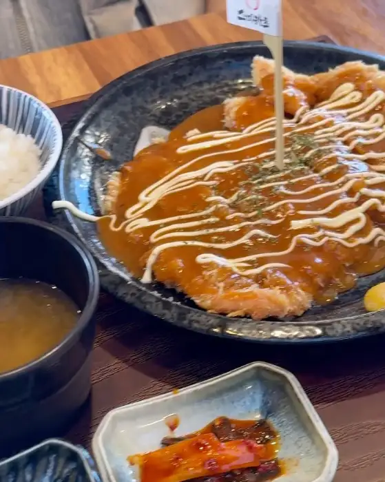 돈까스에 소스가 듬뿍 뿌려져 나오고 밥과 반찬이 함께 나온 모습