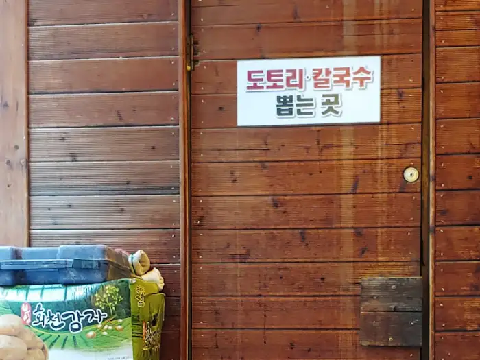 나무 문에 붙어있는 '도토리 칼국수 끓이는 곳' 간판