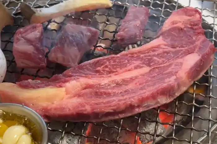숯불 위에서 익어가고 있는 두툼한 한우 스테이크