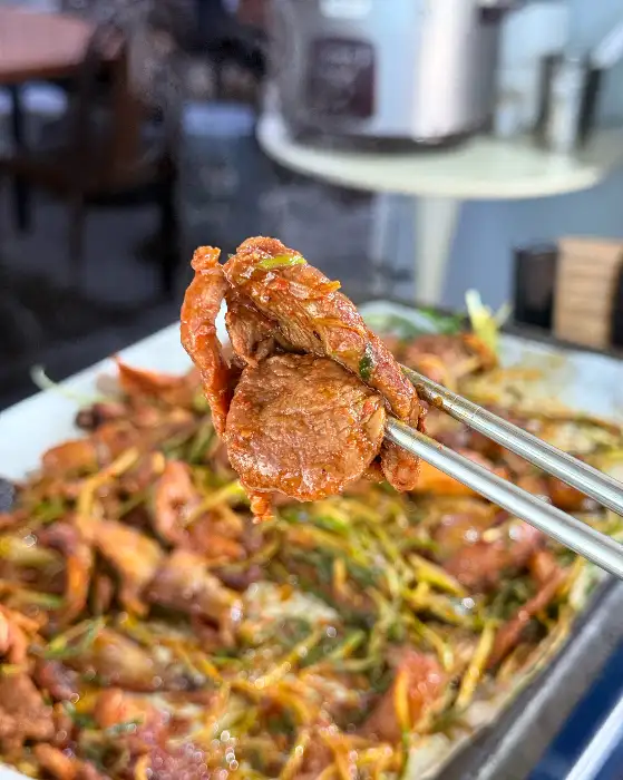 집게로 집어 올린 먹음직스러운 불고기 한 점