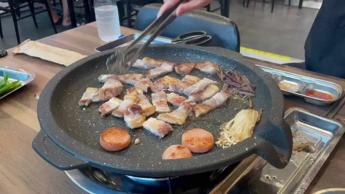 불판 위에서 고기를 굽고 있는 모습, 냉면과 곁들여 먹기 좋게 준비된 모습