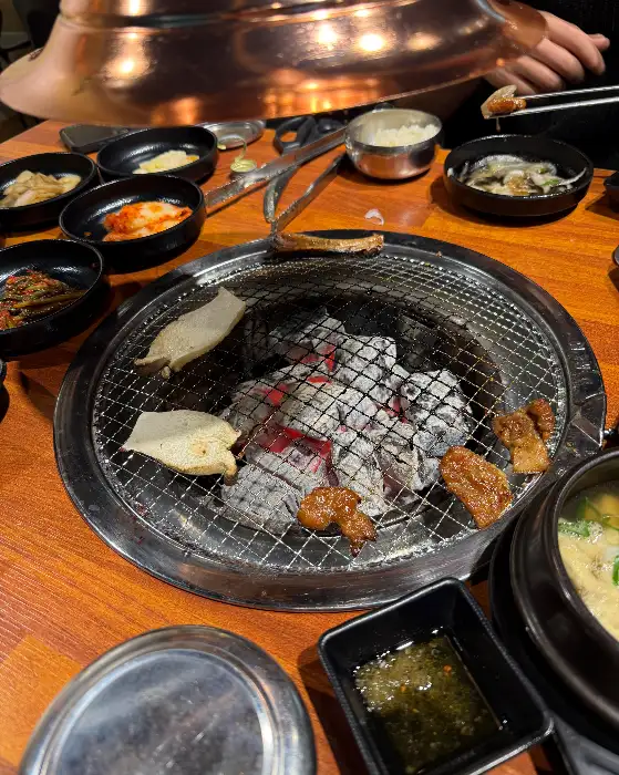 숯불 위에서 구워지는 고기와 곁들임