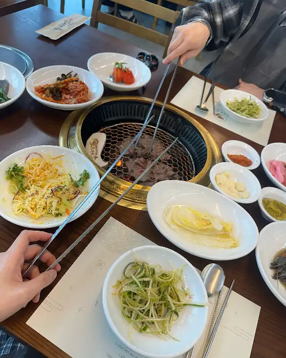 불판 위에서 익고 있는 고기와 다양한 반찬들. 상차림이 풍성하다.