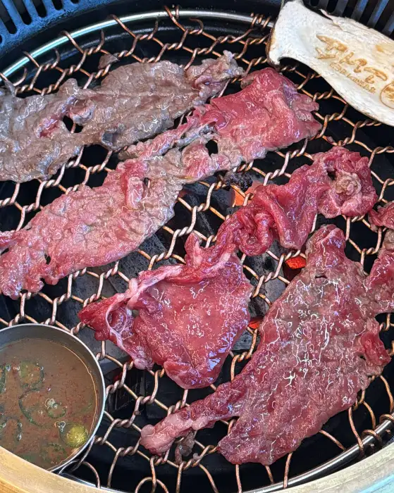 불판 위에 구워지고 있는 얇게 썬 불고기. 숯불의 열기가 느껴진다.