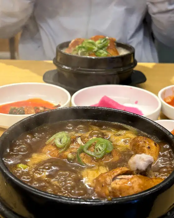 따뜻하게 끓고 있는 삼계탕과 푸짐한 밑반찬