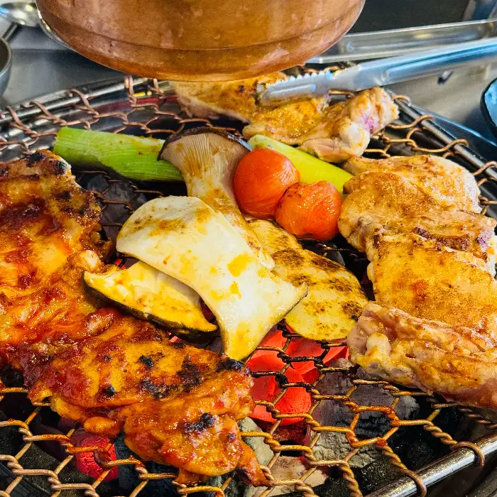 다양한 양념의 닭갈비와 버섯, 파, 토마토가 함께 구워지는 모습